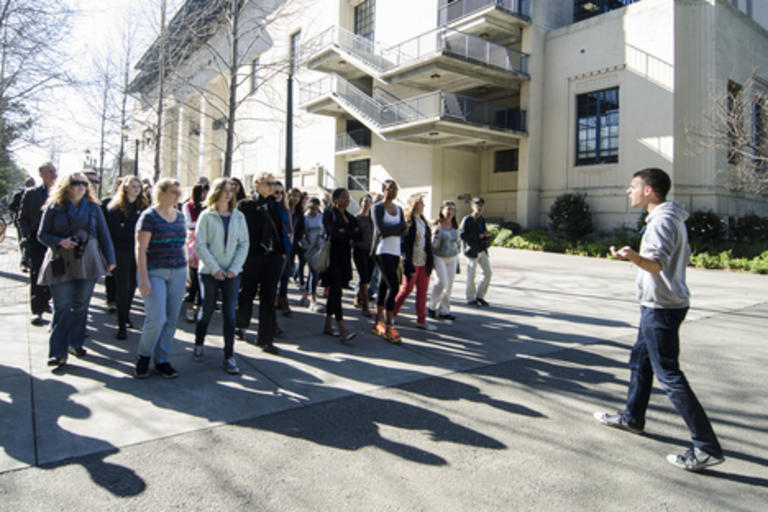 A group of visitors touring the campus, with a tour guide leading them.