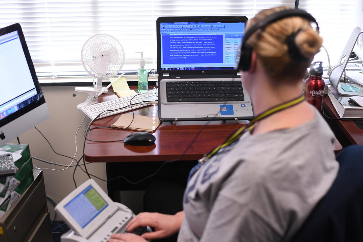 Woman in front of monitor using assistive device for communication