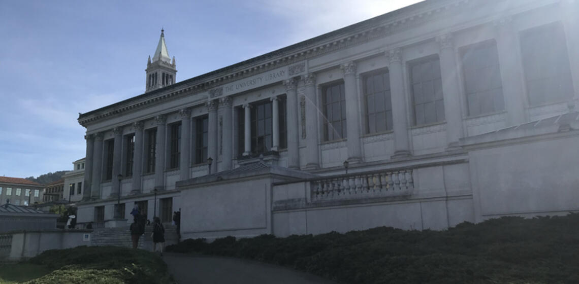 The north side of Doe Library. In front of the building is a staircase. The access path is to the left of the entrance.