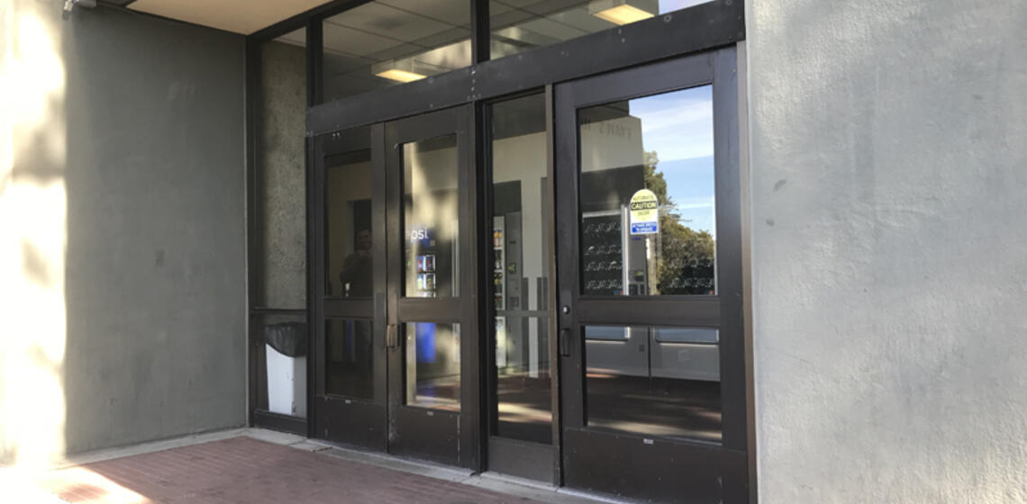 The west entrance to Evans Hall. To the right of the rightmost set of doors is an automatic door opener.