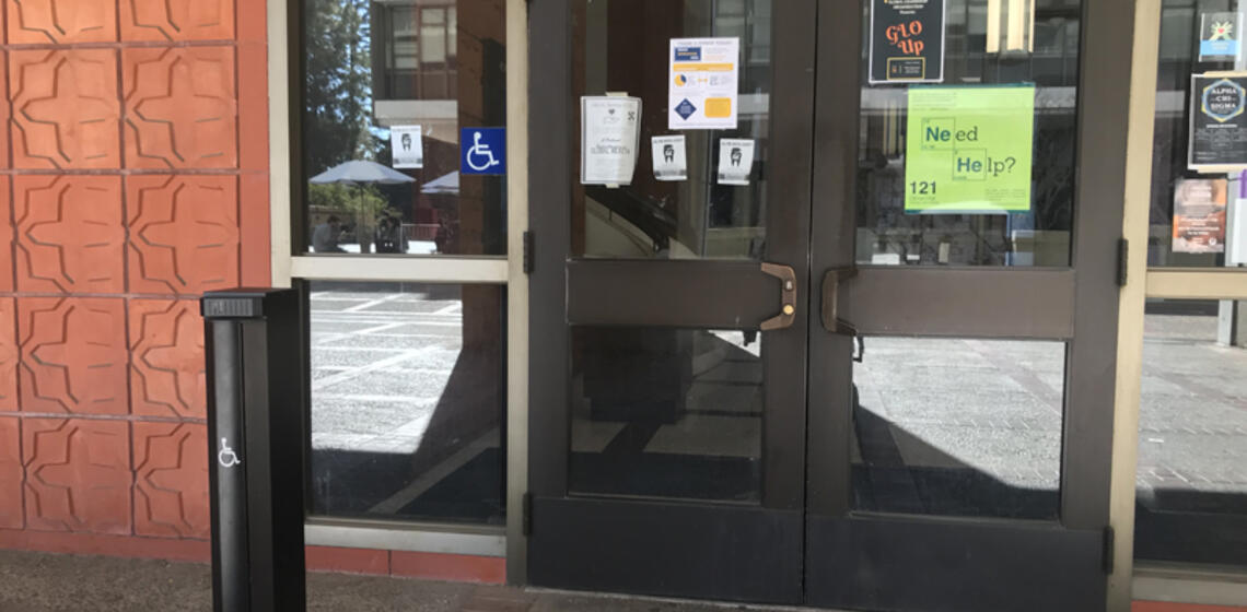 The upper entrance to Latimer Hall, facing south. To the left of its leftmost set of doors is an automatic door opener.