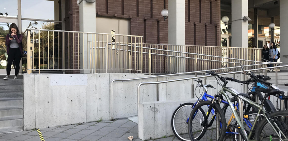 An accessible ramp to MLK's east entrance. To the right of the entrance is an automatic door opener.
