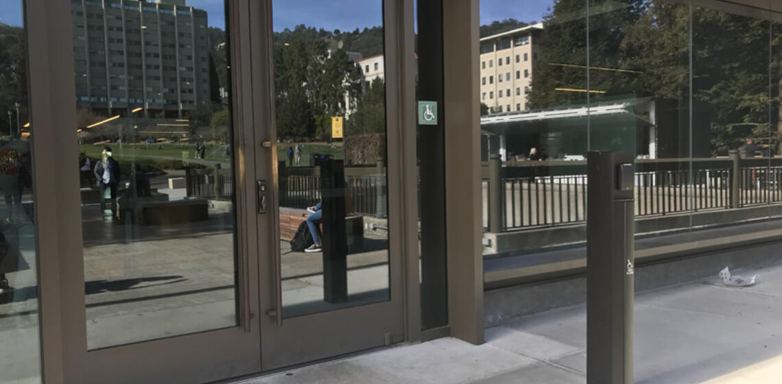 The upper accessible entrance to Moffitt Library, on the east side. To the right of the entrance is an automatic door opener