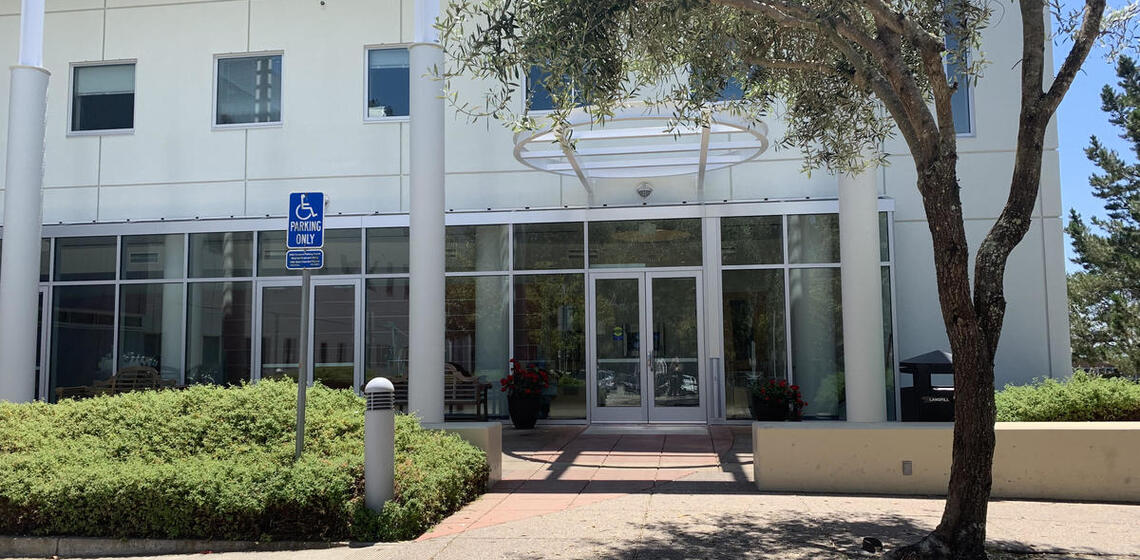 The north facing entrance to Space Sciences Addition. There is a small sitting area with a tree in front of the door