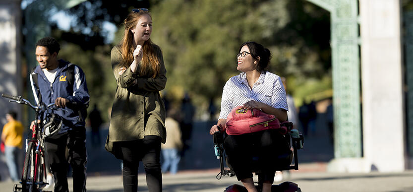 Two students talking near Sather Gate